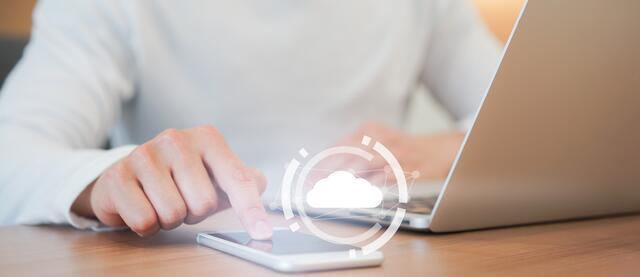 A man using a smartphone in parallel of a laptop.