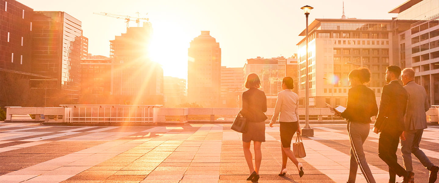 a group of people walking on a brick walkway with a fountain in the background