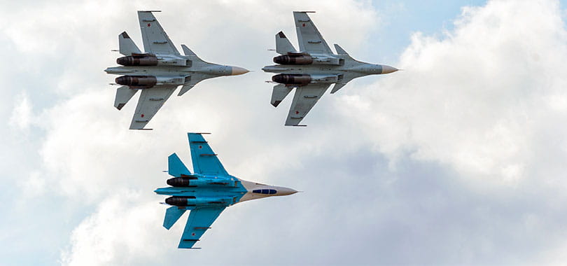 a fighter jet flying through a cloudy blue sky