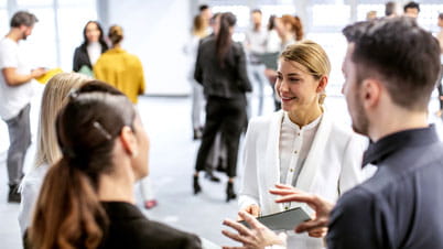 A group of business people networking in small groups within a large open space