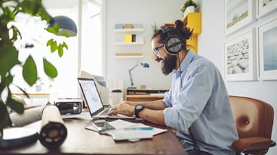 a man wearing headphones and sitting at a desk with a laptop a man wearing headphones and sitting at a desk with a laptop