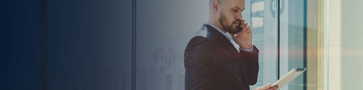 A man walk with a mobile on his ear and a tablet in his other hand.