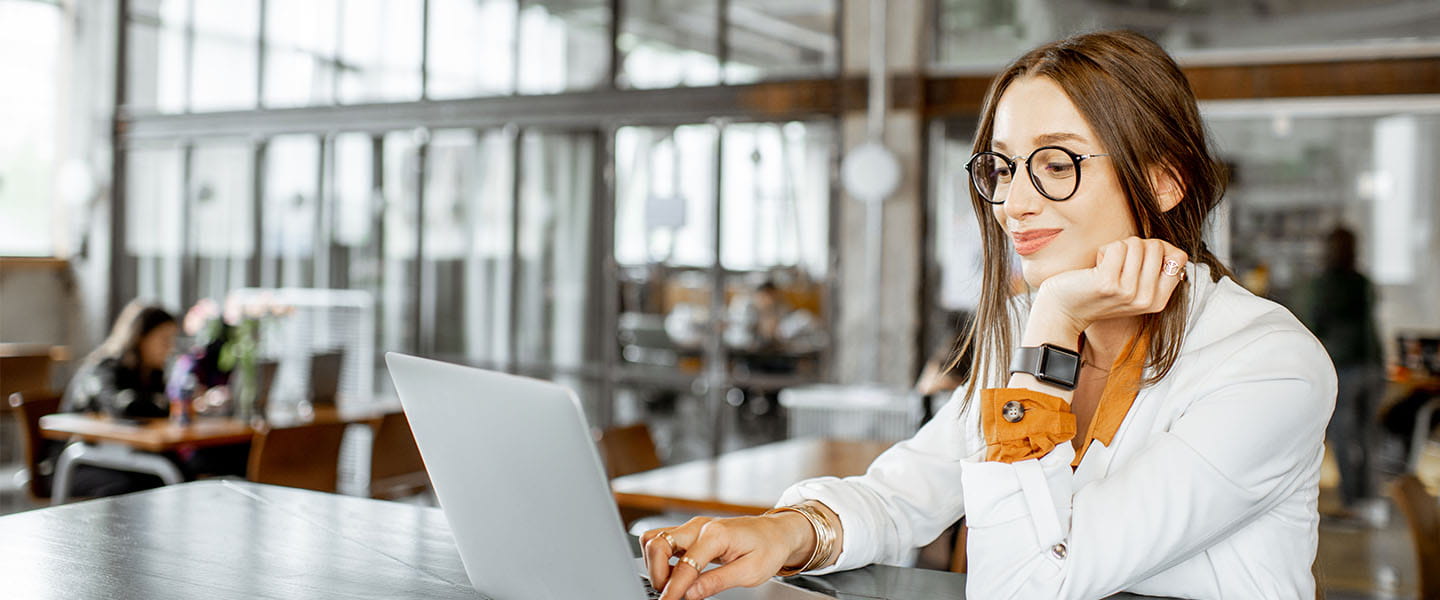 A woman wearing glasses looking at a screen, while typing on a keyboard