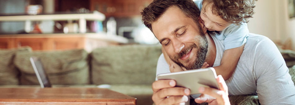 a child putting his arms around the neck of a man who is checking his smartphone a child putting his arms around the neck of a man who is checking his smartphone