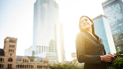 woman using mobile phone with tall buildings in the background woman using mobile phone with tall buildings in the background