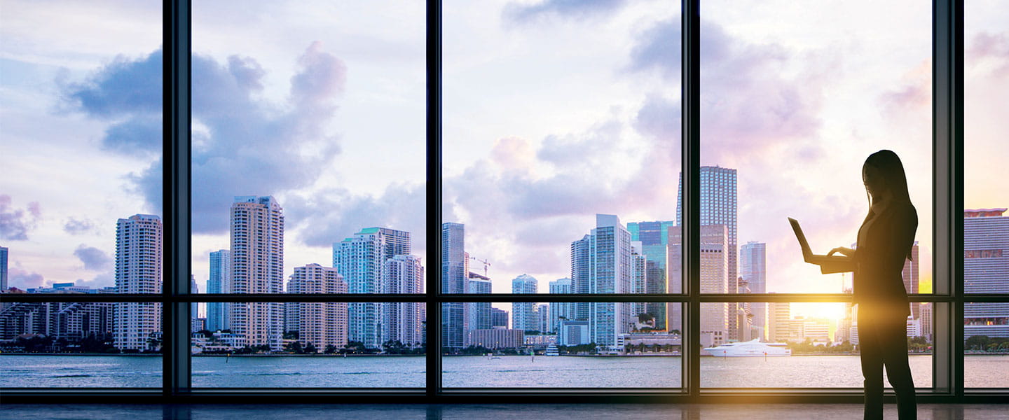 a person standing in front of a window looking out at a city a person standing in front of a window looking out at a city