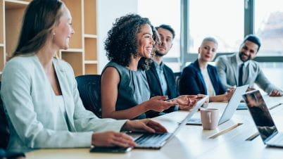 a group of people sitting around a table looking at a laptop a group of people sitting around a table looking at a laptop
