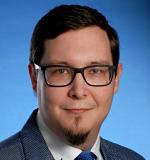 a man wearing glasses and smiling at the camera